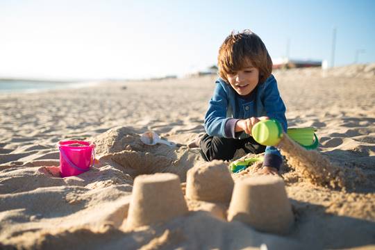 a boy making houses in beach sand learning in a different way