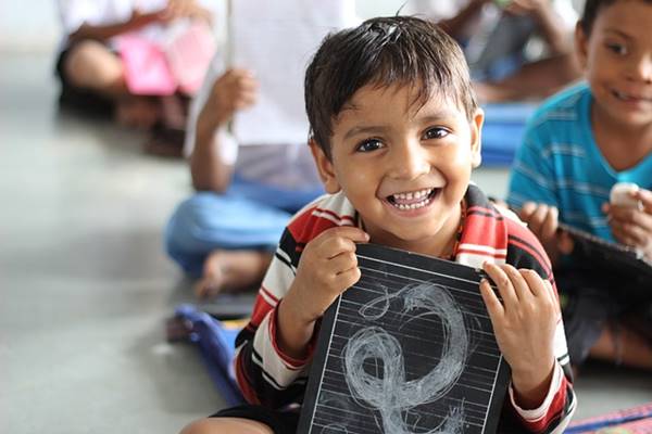 school boy sitting with a slate in hand written in hindi in udaipur school